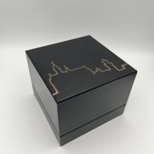 Schwarze Box in Würfelform. In goldener Farbe ist die Silhouette des Schloss Neuschwanstein auf dem Deckel zusehen.